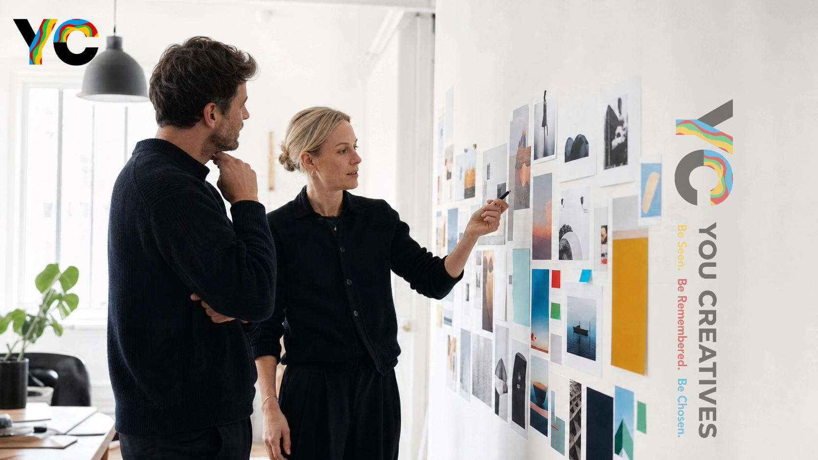 Two colleagues reviewing a brand moodboard pinned on a studio wall