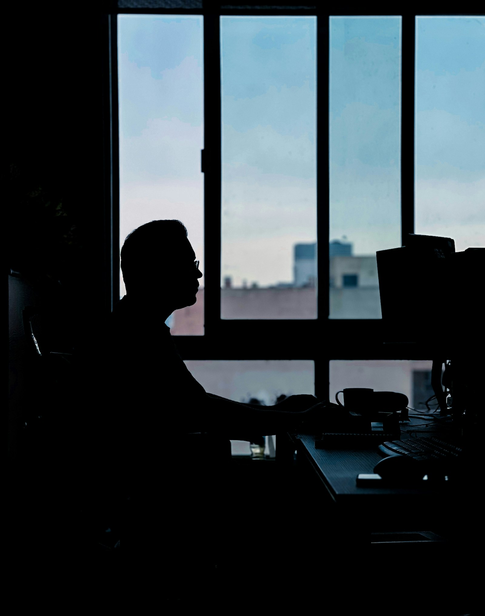 A founder sitting thoughtfully at a desk in front of a window