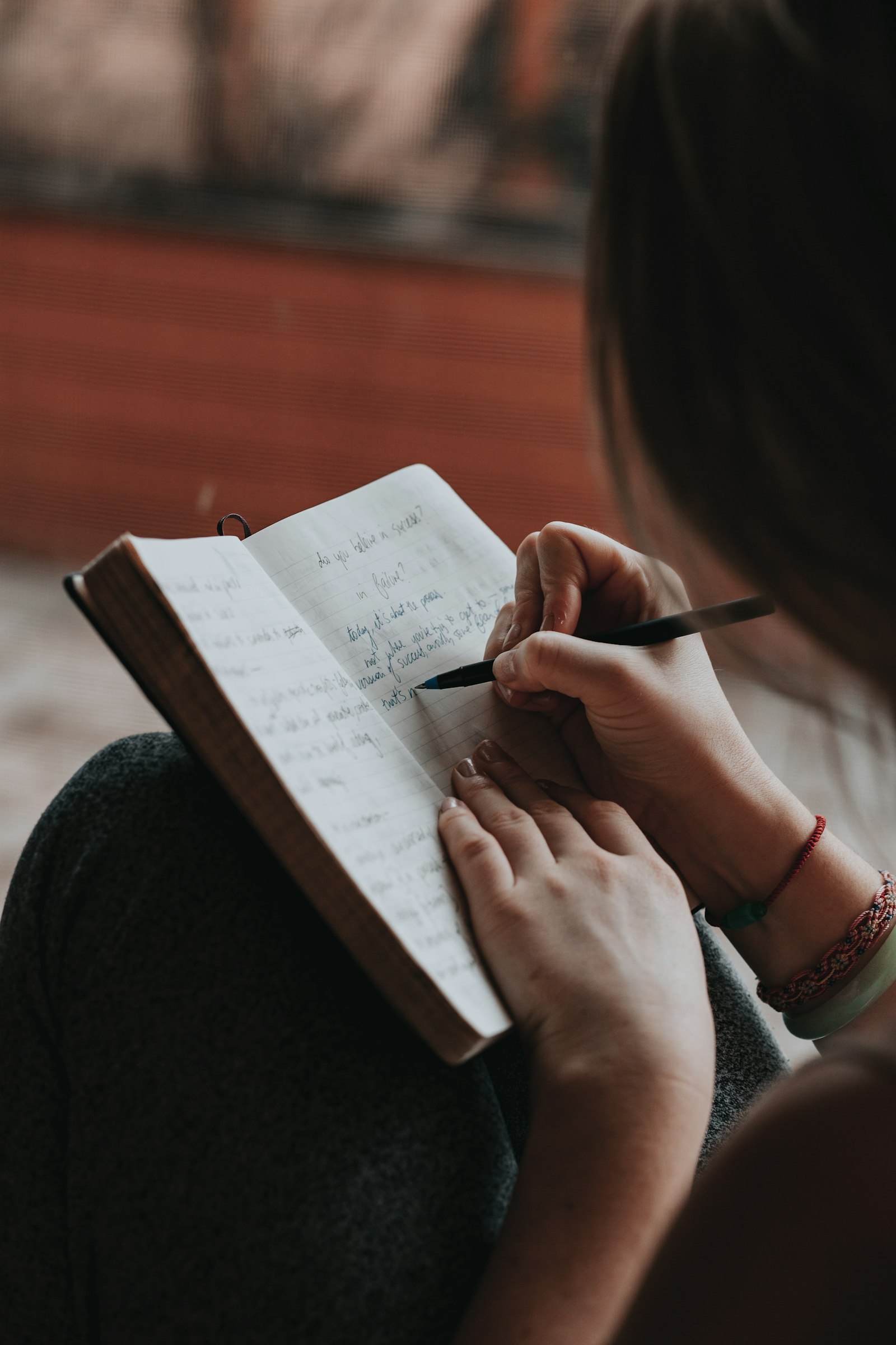Woman writing thoughtfully in a notebook, building a personal brand strategy without daily posting